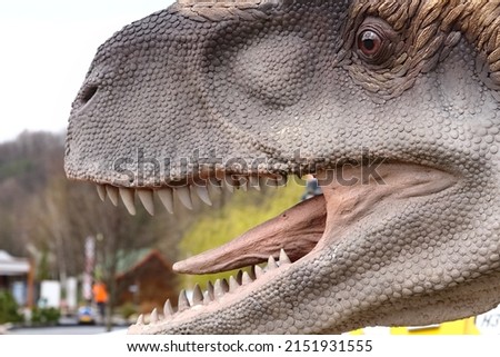 Artificial dinosaur head with sharp teeth and tongue.