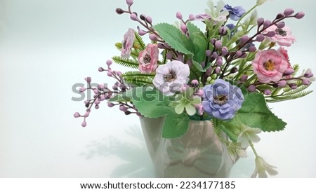 Artificial flowers as a gift. Decorative flowers. Pink, blue and white faux flowers in a ceramic flower vase
isolated on a white background, Artificial flowers in the interior