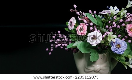Artificial flowers as a gift. Decorative flowers. Pink, blue and white artificial flowers in ceramic flower vase isolated on black background, Artificial flowers in the interior