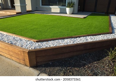 Artificial grass lawn turf with wooden edging in the front yard of a modern Australian home or residential house. - Shutterstock ID 2058373361