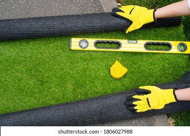 Artificial grass roll and tools in female hands. View above.