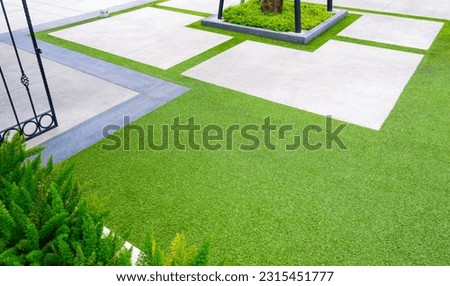 Artificial Grass Turf with White Geometric Cobblestone pavement Floor in Home Garden Background Design, Architecture Exterior Modern Gardening with Green Ornamental Plant Decoration Backdrop