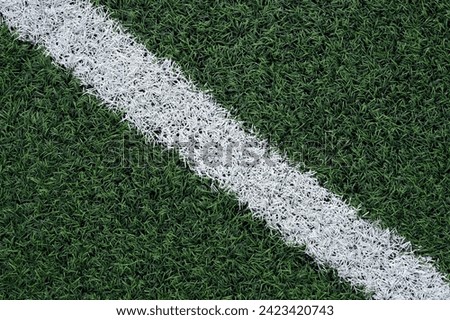 Artificial green grass, Soccer pitch surface, close-up. Top-down view of green synthetic grass with white markings for football arena. Design element for physical activity promotion.