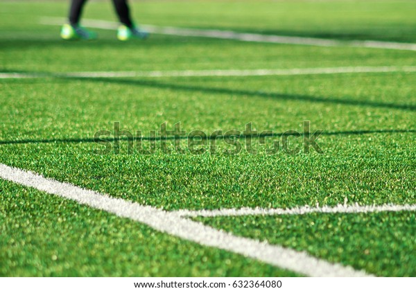 Artificial green grass  with white stripe of\
soccer field. White line on green grass a field of play. Fake Grass\
used on sports fields for soccer and football. Closed-up of\
artificial grass\
background
