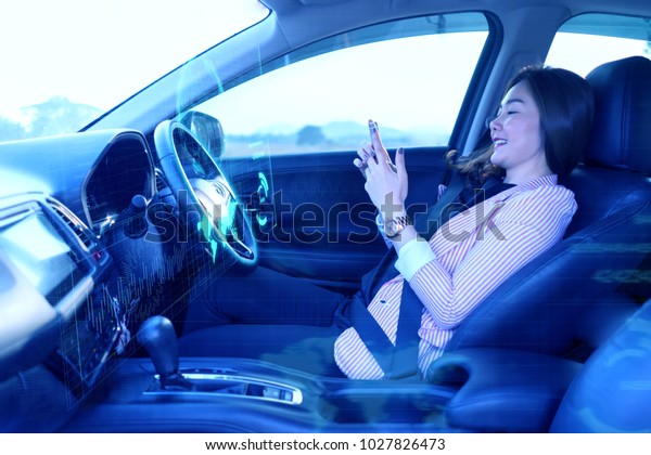 Artificial Intelligence (Ai),Internet of things\
concept,Asian woman using a smartphone in an autonomous car, self\
driving vehicle.heads up technology icon display. automotive\
technology driverless\
car