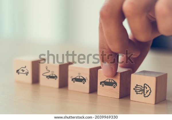 Artificial intelligence in autonomous car technology
concept. A vehicle running self driving mode. Male hold wooden cube
with autonomous car icon. Futuristic technology for the better
human's life. 