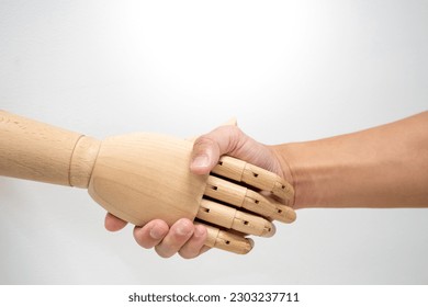 Artificial intelligence business concept. Human shaking hand with wooden mannequin hand which refers to AI. - Powered by Shutterstock