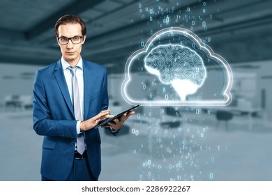 Artificial Intelligence hardware concept. Young businessman with tablet and glowing cloud brain and circuit coding hologram on blurry office background. Data processing, ai trading, machine learning