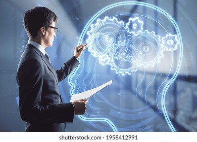 Artificial intelligence and machine learning concept with businessman writing on virtual board with human head silhouette and gears instead brain inside