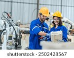 Artificial intelligence robotic technician concept, Factory engineer inspecting on machine with smart tablet. Worker works at heavy robot arm. Welding with remote system in an manufacturing industrial