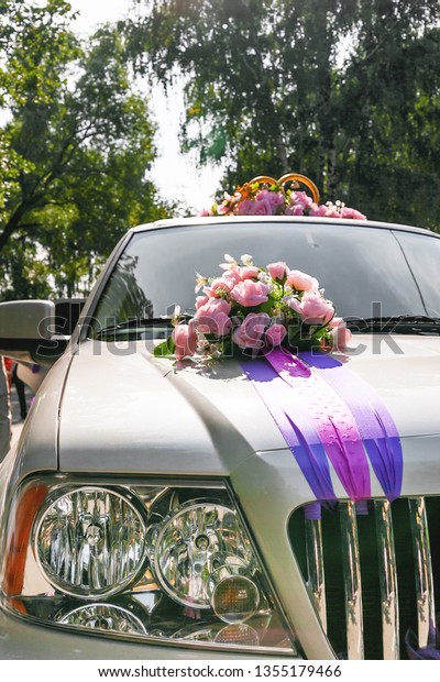 Artificial pink roses and golden rings with\
bells. Car decoration for wedding\
ceremony.