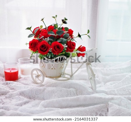 Artificial red rose flowers in bike toy on table bouquet bucket Bicycle with soft tone for festive background or wallpaper copy space for lettering ,Valentine's day romantic love ,birthday card 