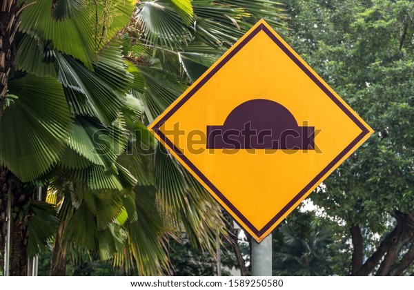 Artificial road roughness; car speed limit\
sign among tropical\
vegetation