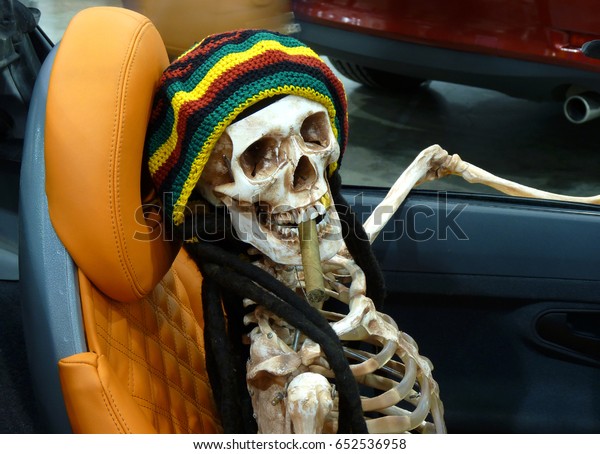 Artificial
skeleton-rastaman sits in a car with a
cigar
