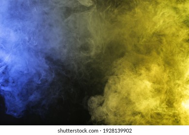 Artificial smoke in blue yellow light on black background