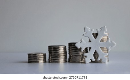 An artificial snowflake leans against a stack of coins. A creative photo illustrating economic stagnation and falling profits
