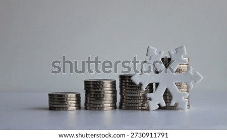 An artificial snowflake leans against a stack of coins. A creative photo illustrating economic stagnation and falling profits

