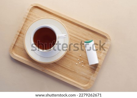 artificial sweetener container and tea cup on table 