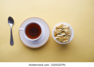 artificial sweetener powder in a packet and cup of tea on yellow background  - Shutterstock ID 2225523791