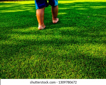 Artificial turf background. Tender baby foots on a green artificial grass floor