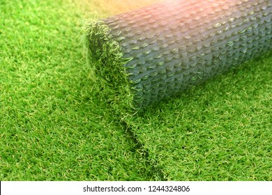 Artificial turf laying background. Roll of an synthenic grass layer. Greenering of the yard with an artificial lawn. 