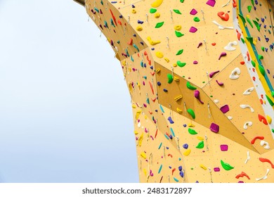 Artificial yellow wall for climbing training with colorful grips and stops