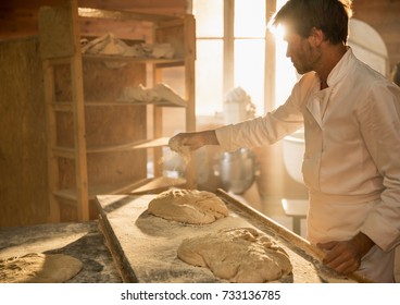 In an artisan bakery, a baker prepare the bread dough. The morning sun comes in through the window - Powered by Shutterstock