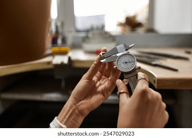 An artisan carefully measures jewels with precision tools in a bright workshop. - Powered by Shutterstock