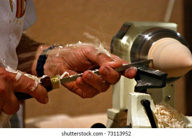 An artisan is carving wood accurately. The hands are full of wood shavings - Shutterstock ID 73113952