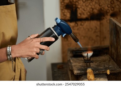 An artisan focuses intently while using a torch to shape exquisite jewelry in her studio. - Powered by Shutterstock