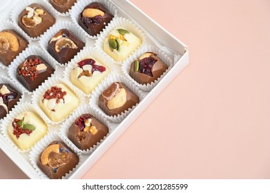 Artisan Handcrafted Chocolate Bonbons Packaged In A Gift Box. Overhead View Of Mixed Chocolate Candies On Pink Surface