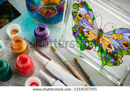 Artisan painting with stained glass paints on a glass.
