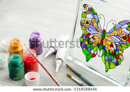 Artisan painting with stained glass paints on the glass surface.