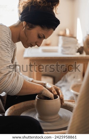 Similar – Young female sitting by table and making clay or ceramic mug