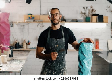 Artisan sculptor artist of Arab appearance smiling at camera against backdrop of the workshop and his product - Shutterstock ID 2186819091