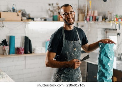 Artisan sculptor artist of Arab appearance smiling at the camera against the backdrop of workshop and his product - Shutterstock ID 2186819165