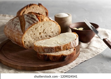 Artisan sliced toast bread with butter and sugar on wooden cutting board. Simple breakfast on grey concrete background. Closeup view