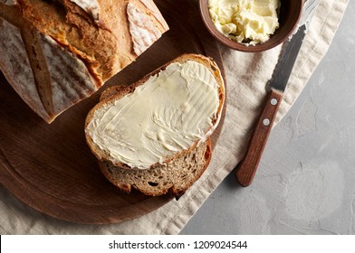 Artisan sliced toast bread with butter and sugar on wooden cutting board. Simple breakfast on grey concrete background. Top view - Shutterstock ID 1209024544