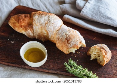 Artisan sourdough bread served with olive oil and thyme on wooden cutting board. Selective focus - Powered by Shutterstock