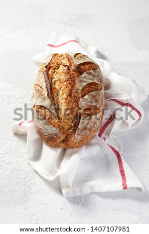 Artisan sourdough homemade loaf of bread on grey concrete background. Natural light with soft shadows, closeup view