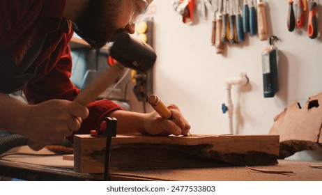 Artisan using bench vise to hold timber block, carving intricate designs into wood using chisel and hammer. Artist uses vice tool to clamp piece of wood, shaping log with tools, camera B close up shot - Powered by Shutterstock