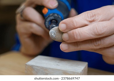 Artisan woman making a hole in a stone with a rotary tool seen up close - Powered by Shutterstock