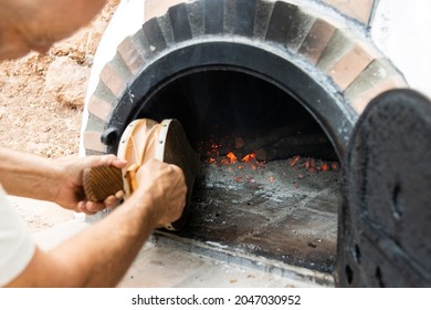 Artisan Wood-fired Oven And Man's Hands Blowing The Embers With A Bellows