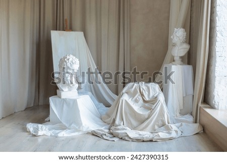 Artisan workshop. Interior studio with Workspace of artist. White sculptures, plaster bust, marble statue and Gypsum head on concrete wall background. Creative painting Studio of artist with easel. 