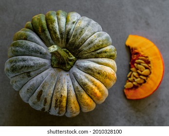 Artisanal organic pumpkin cut and sliced with yellow and green skin and a  pattern on the rind. Orange green skinned pumpkin from an organic farmers' market in germany. Homegrown vegetables.