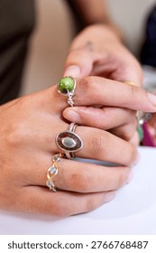 Artisan's hands displaying three unique, personally crafted rings, showcasing the intricate details of handmade jewelry design