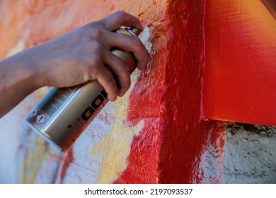 An Artist Adds Some Gold-colored Spray Paint To A Mural On The Roof Of A Building. 