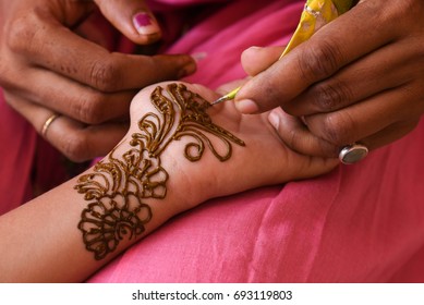 Artist applying beautiful henna tattoo Arabic design to a Woman's or Indian bride's hands at City Palace on wedding in Rajasthan. Mehndi is a popular body art among women of India, Pakistan, Africa.