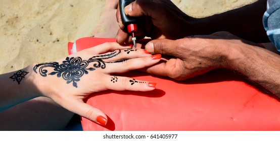 Artist Applying Henna Tattoo On Women Hands