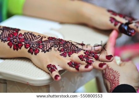 Artist applying henna tattoo on bride hands. Mehndi is traditional Indian decorative art. Close-up
